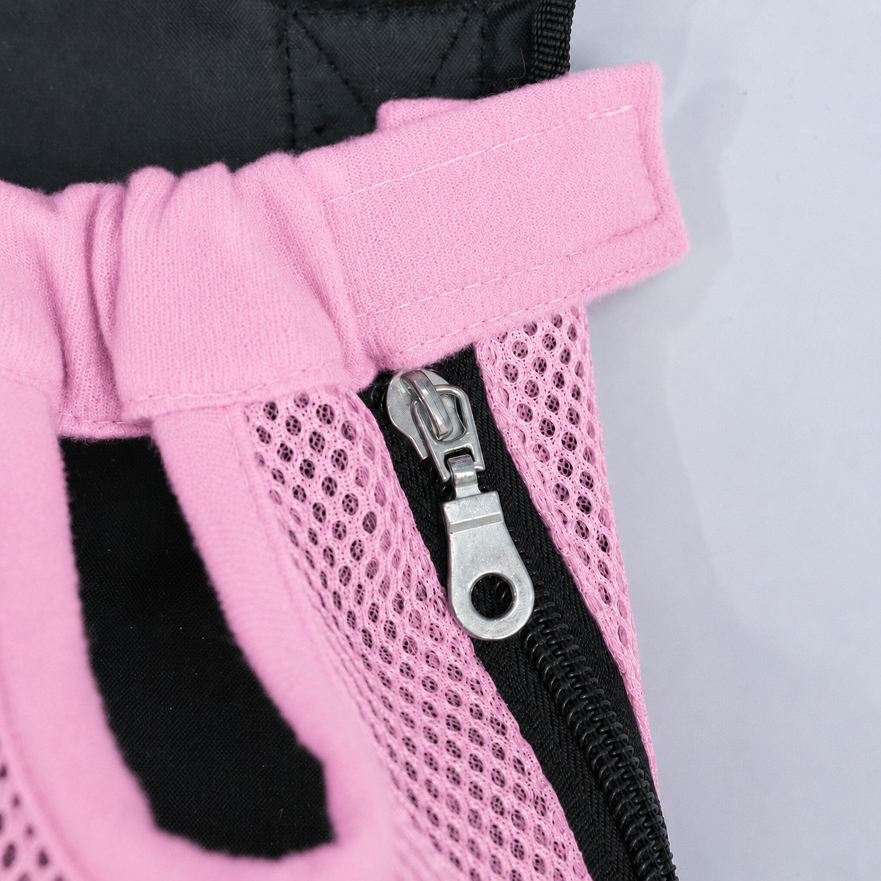 Gros plan sur la fermeture éclair latérale et la patte auto-agrippante du sac L'Éclaireur rose, en maille respirante rose