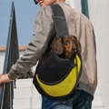 Petit teckel porté dans le sac de transport bandoulière Le Baladin jaune, la tête sortie de la maille, un homme le porte en travers du buste dans la rue — Maison Pattounes