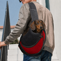 Petit teckel porté dans le sac de transport bandoulière Le Baladin rouge, la tête sortie de la maille, un homme le porte en travers du buste dans la rue — Maison Pattounes