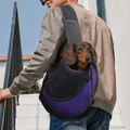 Petit teckel porté dans le sac de transport bandoulière Le Baladin violet, la tête sortie de la maille, un homme le porte en travers du buste dans la rue — Maison Pattounes